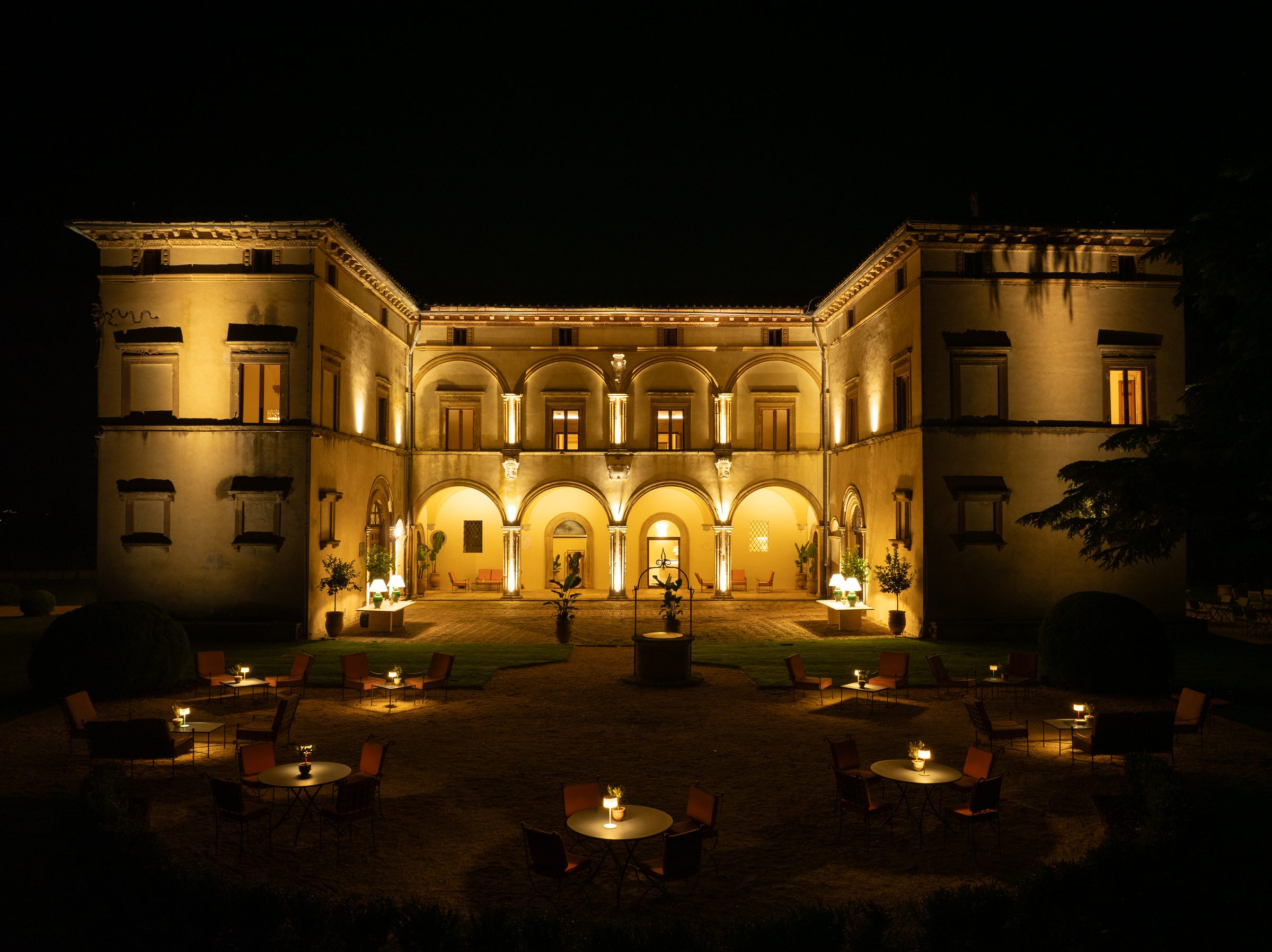 Il cortile di Volte Alte illuminato di notte, con i tavolini e le candele sul prato