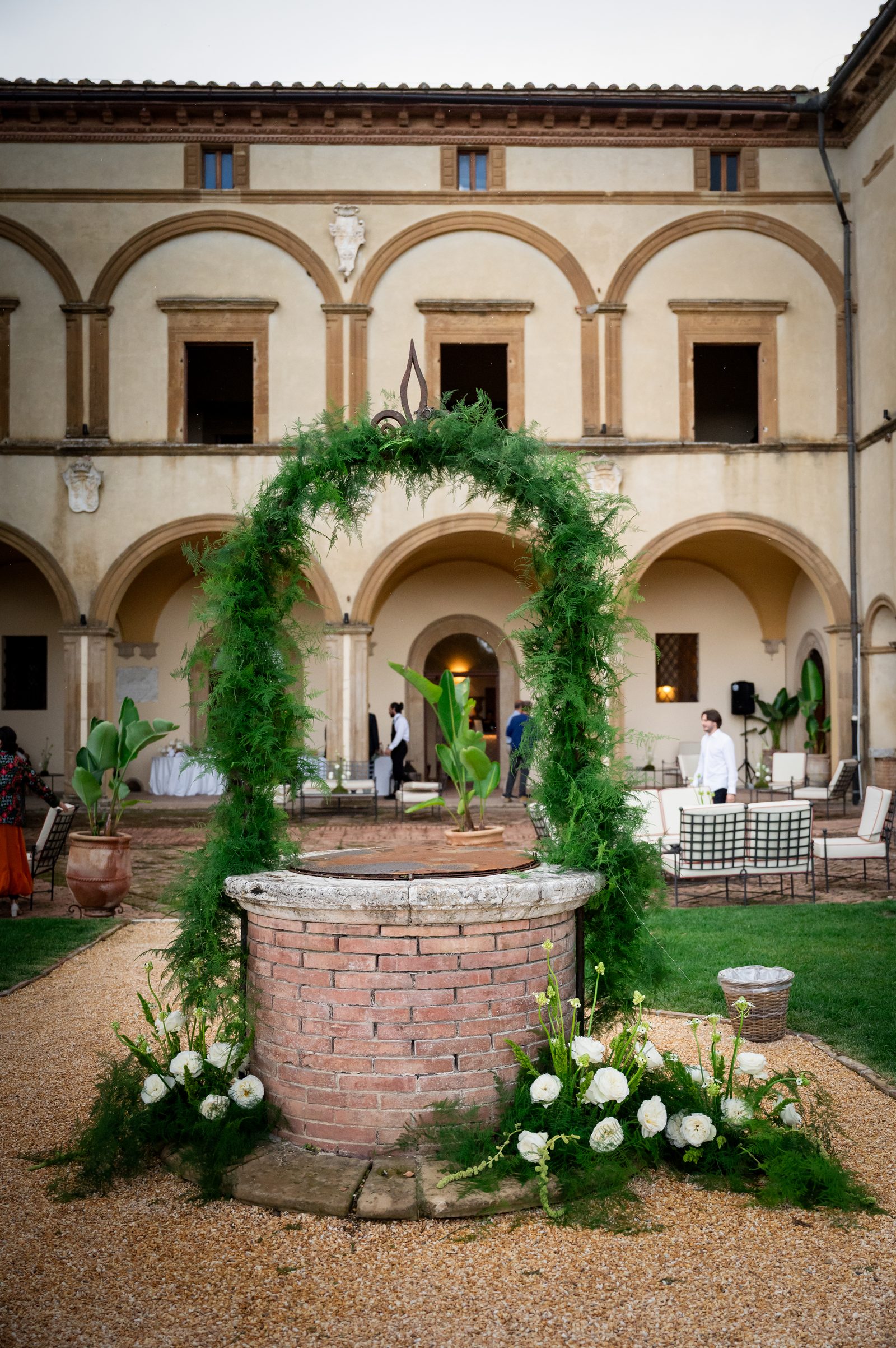 Il pozzo nel cortile di Volte Alte allestito con un arco di verde e fiori bianchi