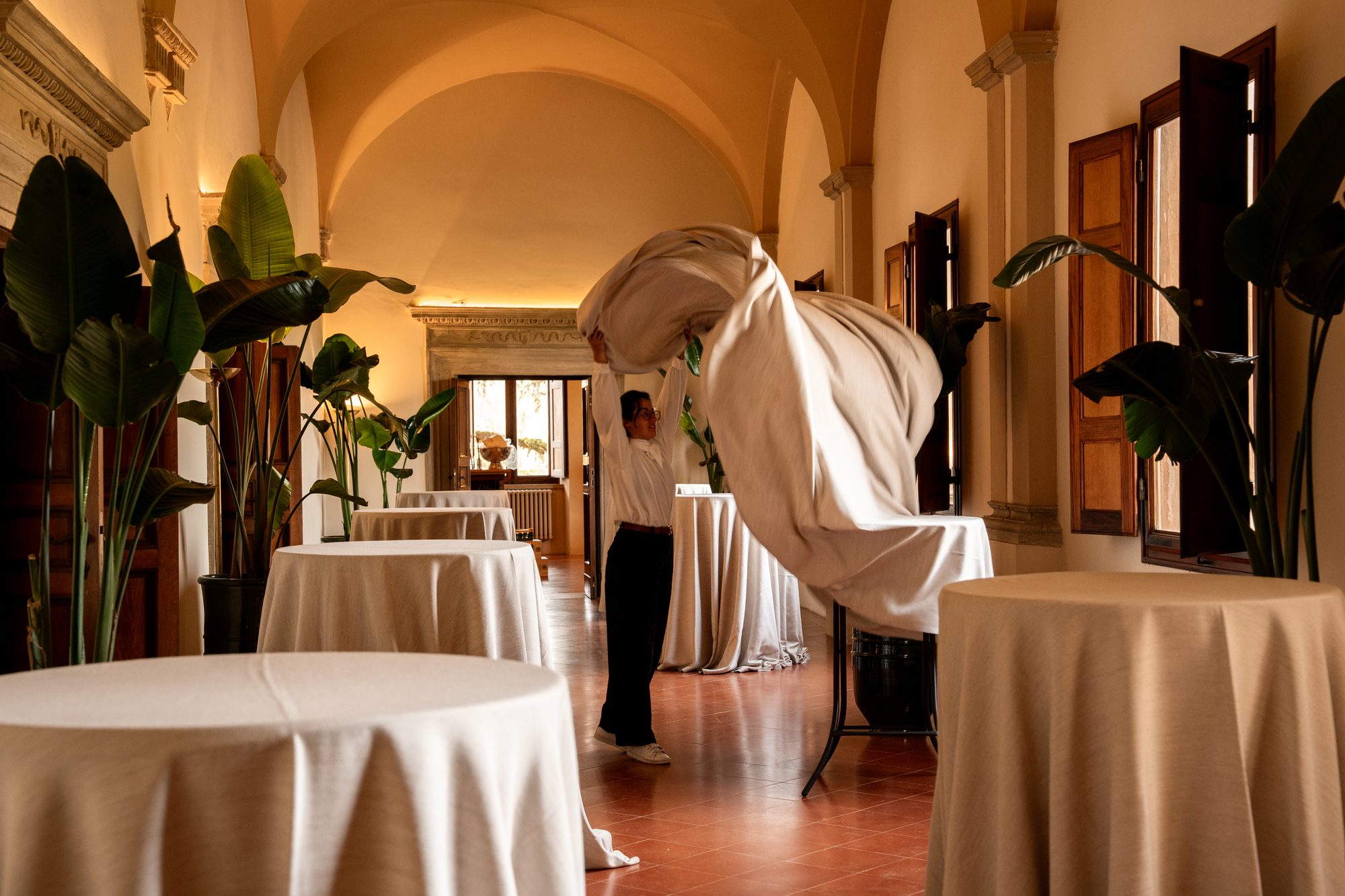 Una tovaglia lanciata in aria sui tavoli alti nella galleria di Volte Alte, durante l'allestimento