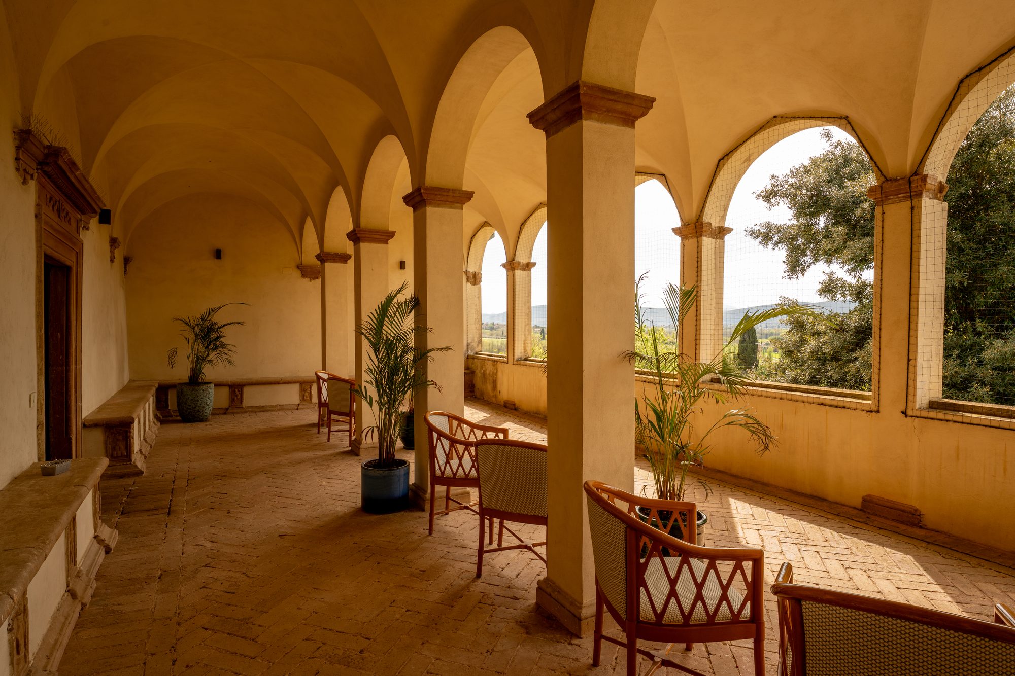 La loggia del primo piano di Volte Alte: gli archi sulle colline, la panca di pietra e il pavimento in cotto